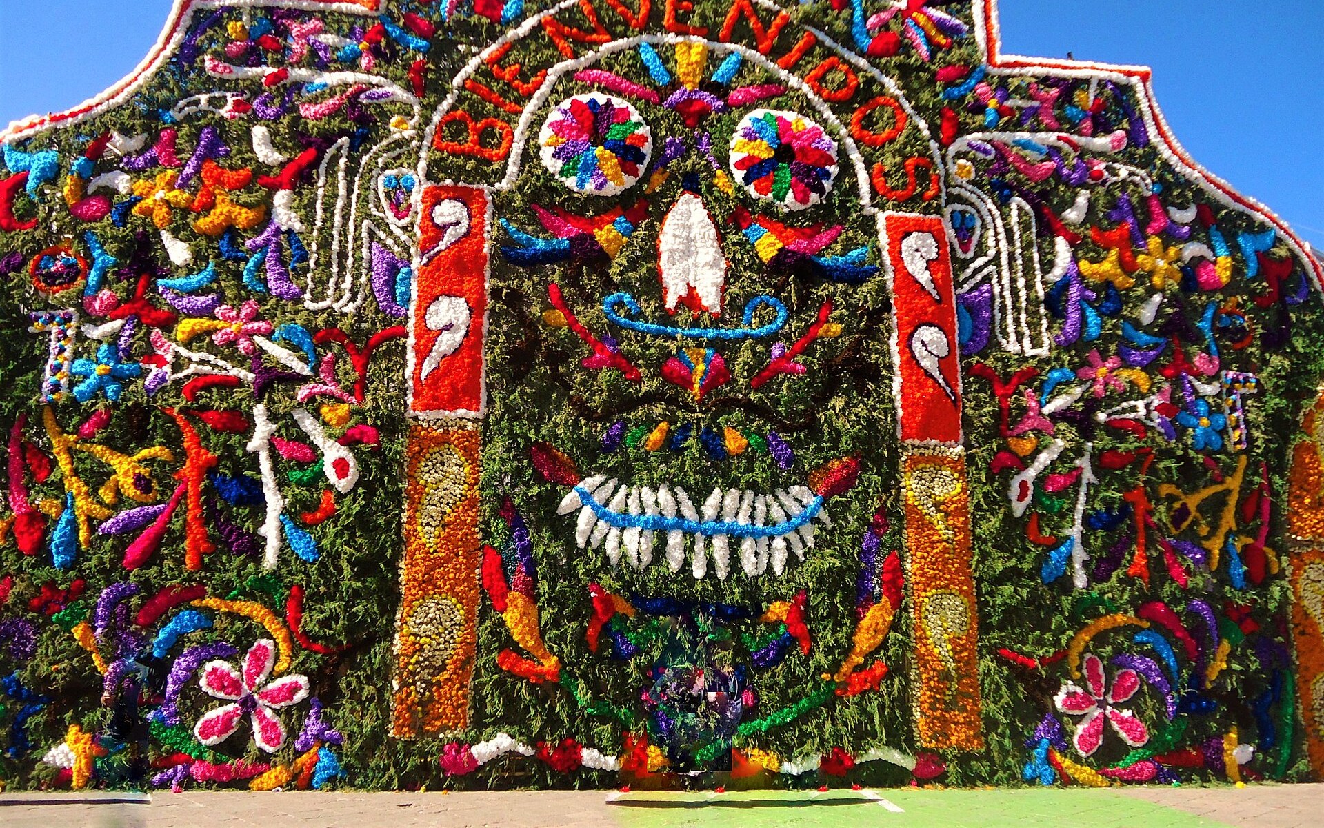 A giant Day of the Dead ofrenda arch covered in marigolds and bright flowers in the shape of a smiling skull, Mexico